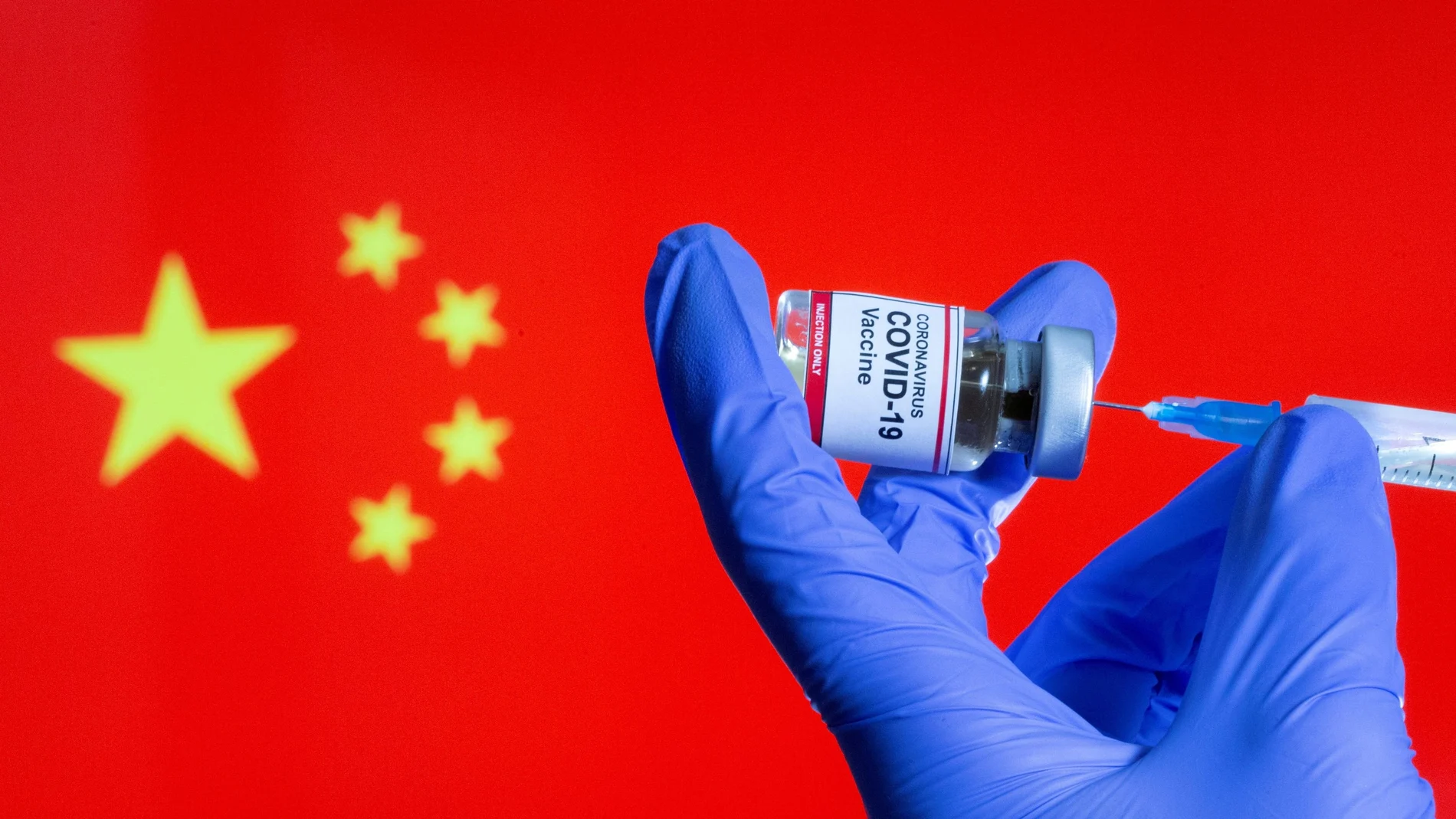 FILE PHOTO: FILE PHOTO: A woman holds a small bottle labeled with a "Coronavirus COVID-19 Vaccine" sticker and a medical syringe in front of displayed China flag in this illustration taken, October 30, 2020. REUTERS/Dado Ruvic/File Photo/File Photo
