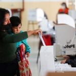 A Peruvian woman residing in Argentina holds a baby as she casts her vote at a polling station in a public school, in Peru's presidential election, in Buenos Aires, Argentina April 11, 2021. REUTERS/Agustin Marcarian