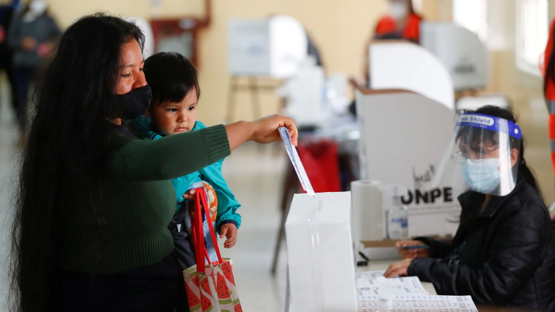 A Peruvian woman residing in Argentina holds a baby as she casts her vote at a polling station in a public school, in Peru's presidential election, in Buenos Aires, Argentina April 11, 2021. REUTERS/Agustin Marcarian