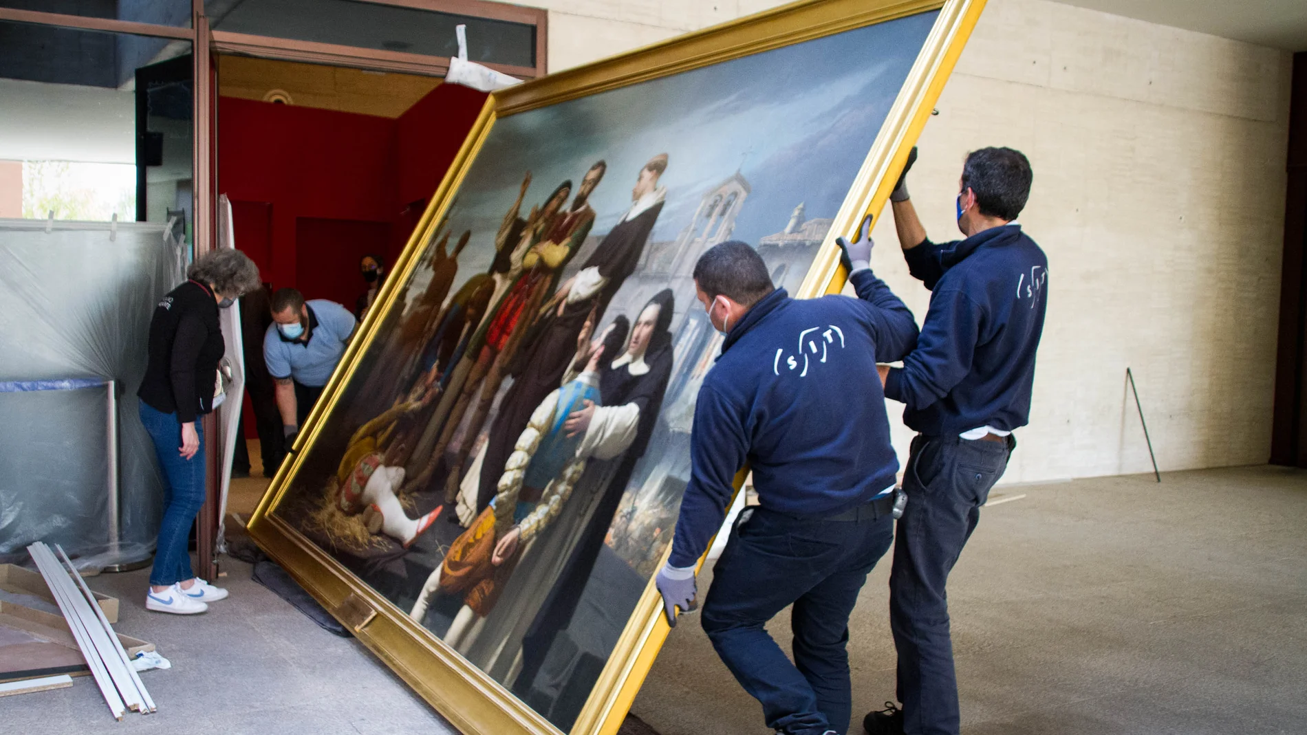 Unos operarios trasladan el cuadro "Los comuneros Padilla, Bravo y Maldonado en el patíbulo" en el hall, de las Cortes de Castilla y León