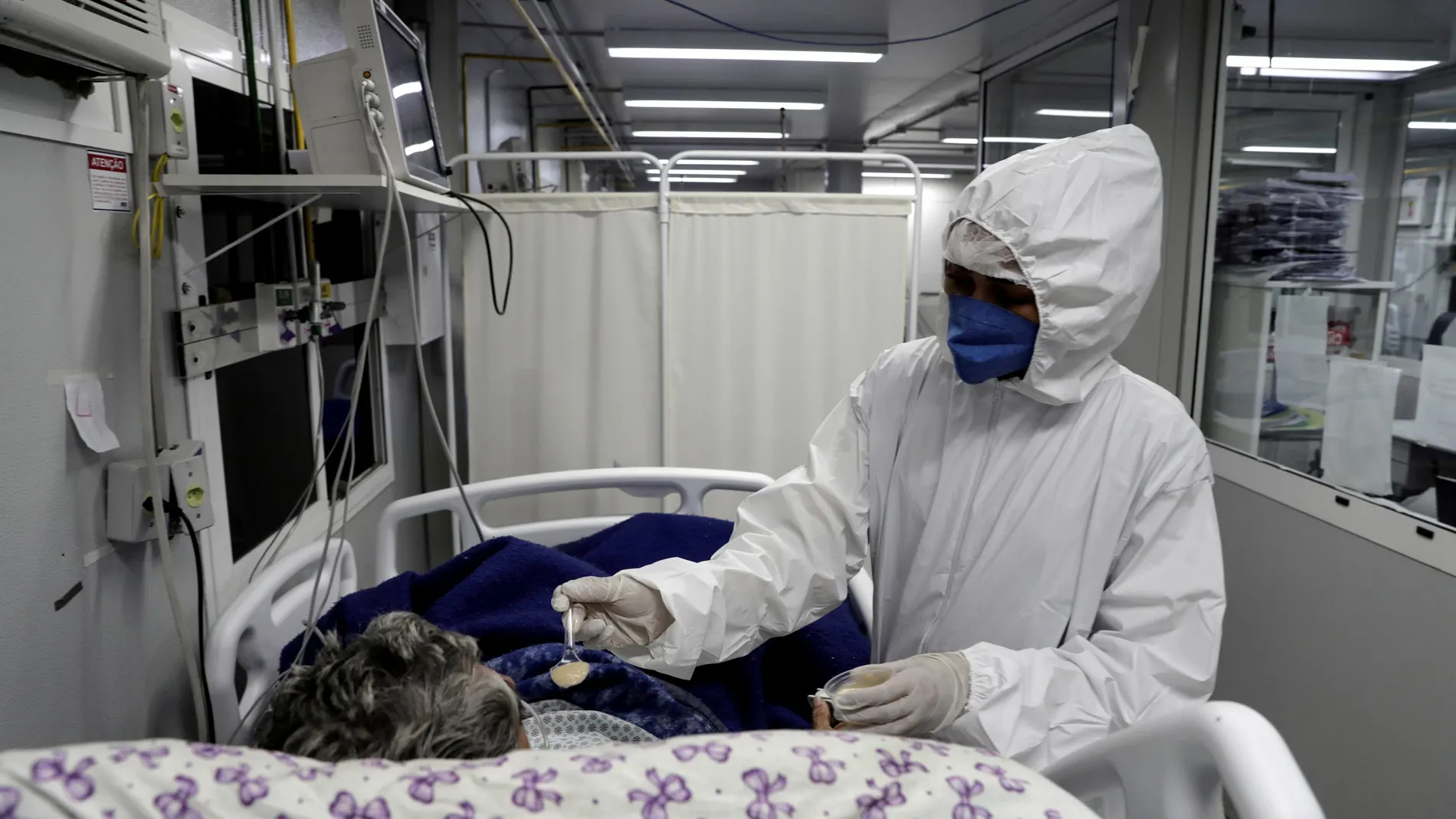 Una enfermera alimenta a un paciente contagiado por covid-19 hoy, en el Hospital General de Nova Iguaçú, en el área metropolitana de Río de Janeiro (Brasil