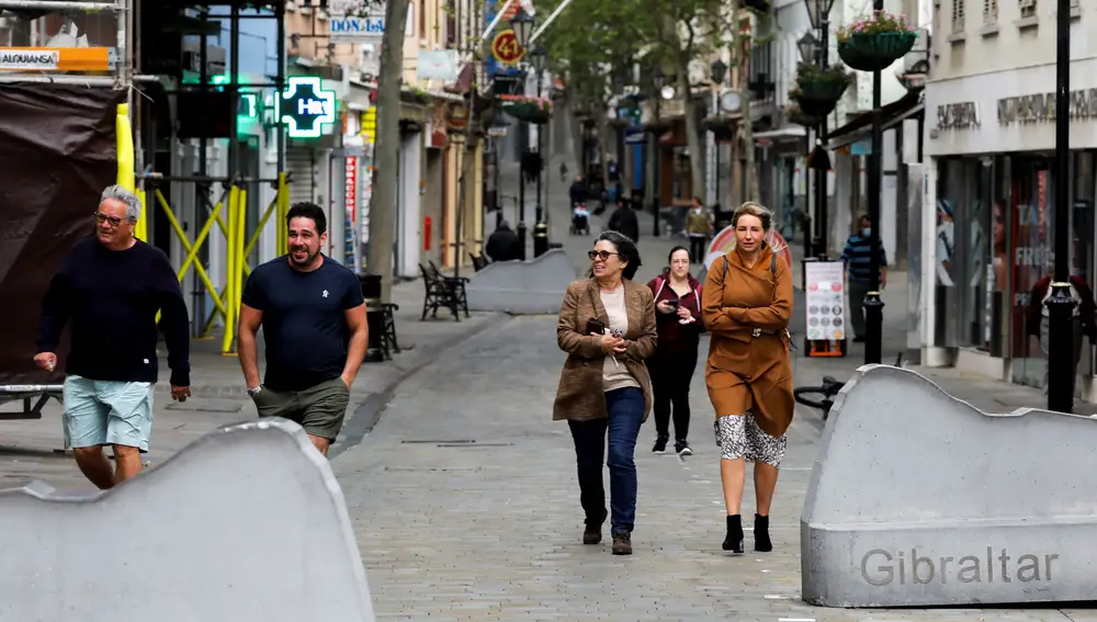 People walk without face masks in Main street as from today the British territory eases mask usage outdoors after its successful vaccination campaign against the coronavirus disease (COVID-19), in Gibraltar, March 28, 2021. REUTERS/Jon Nazca