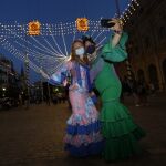 Dos mujeres vestidas de flamenca se hacen un "selfie" en el centro de Sevilla