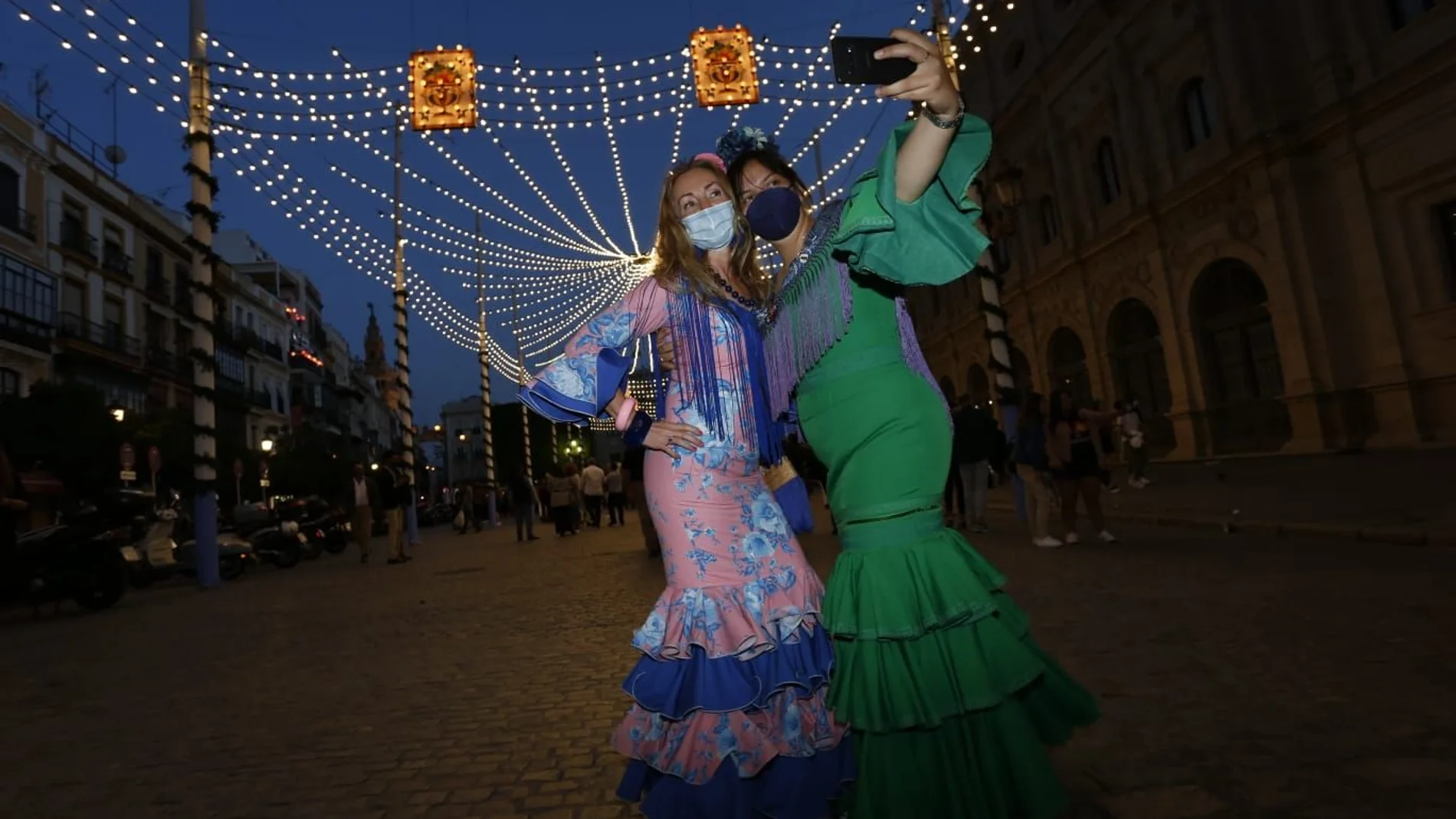 Dos mujeres vestidas de flamenca se hacen un "selfie" en el centro de Sevilla