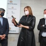 La presidenta de Sodeva, Inmaculada Toledano, sujeta una botella del Vino Museo en presencia del diputado provincial, Agapito Hernández, , y del presidente de los sumilleres de España, Pablo Martín