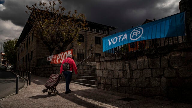 Una vecina de Colmenarejo cruza con el carro de la compra entre carteles electorales