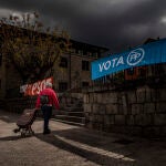 Una vecina de Colmenarejo cruza con el carro de la compra entre carteles electorales