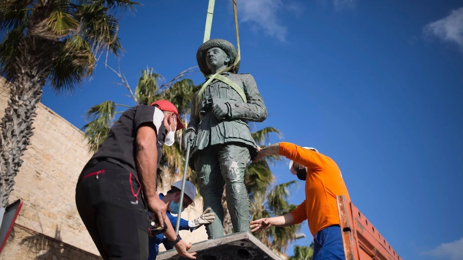 Operarios proceden a retirar la estatua dedicada al "comandante Francisco Franco" situada ante la muralla de Melilla La Vieja