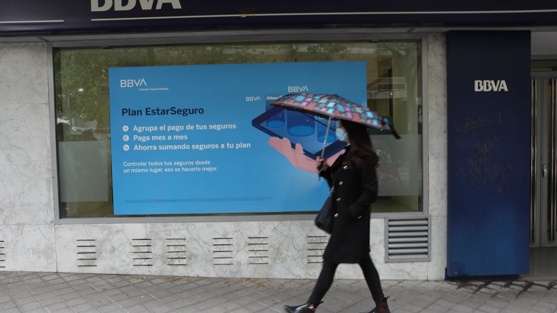 Una persona pasa por delante de una oficina de BBVA en Madrid. La dirección de BBVA ha planteado el despido de 3.798 personas y el cierre de 530 oficinas