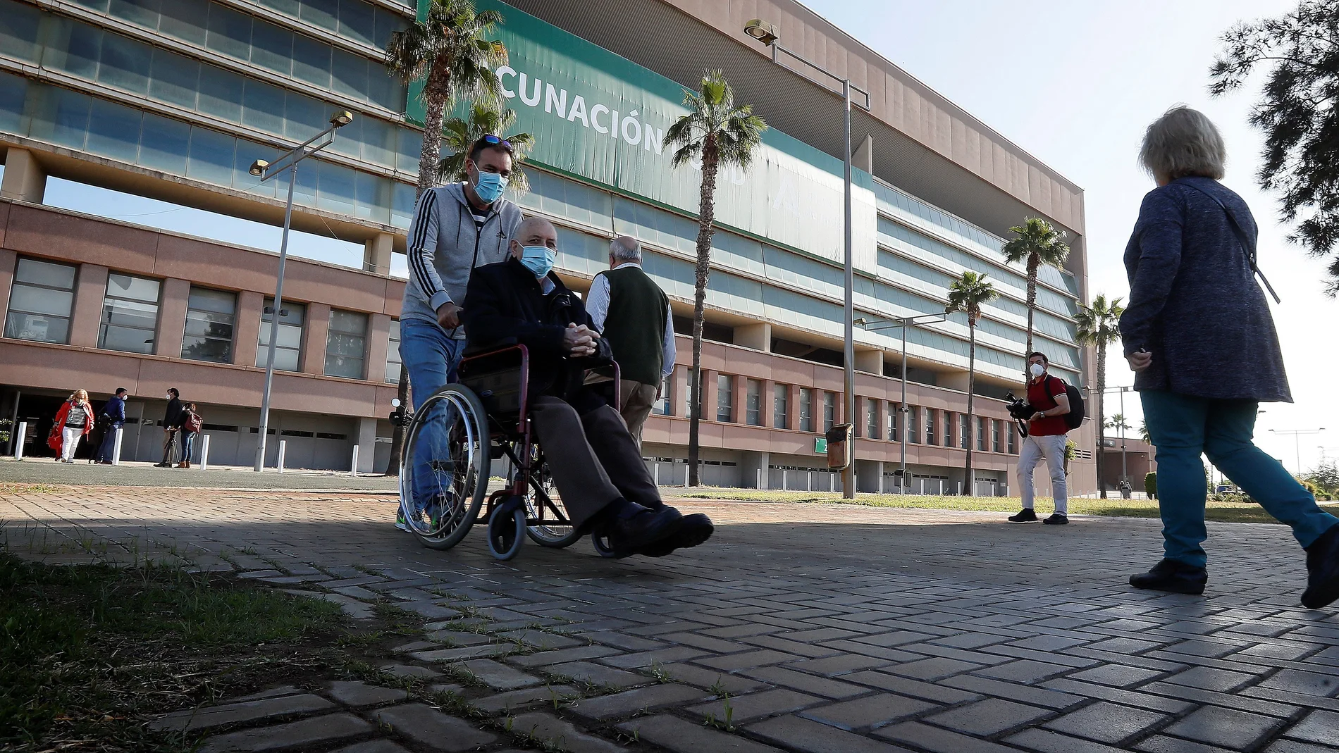 Varias personas entran y salen del estadio de la Cartuja de Sevilla para vacunarse