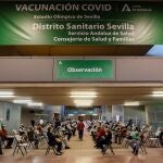 Algunas de las personas que esperan su turno para ser vacunadas hoy en el estadio de la Cartuja de Sevilla que ha comenzado este jueves a funcionar como centro de vacunación masiva frente a la Covid