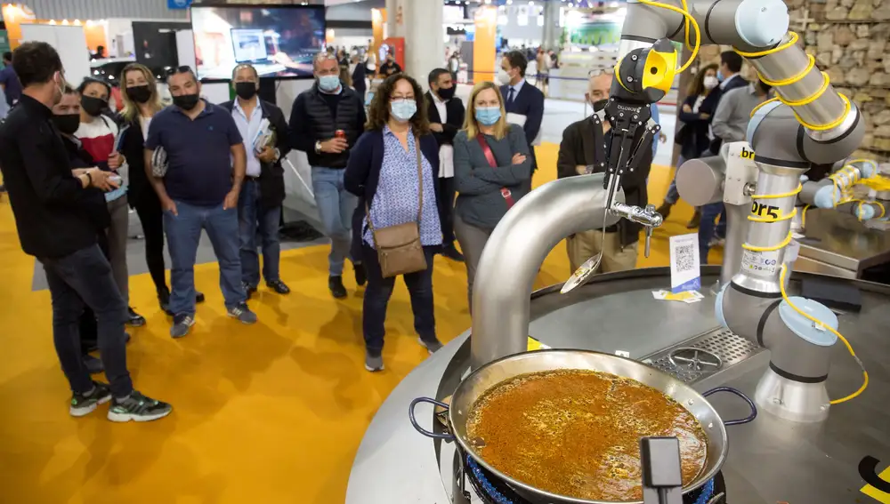 GRAFAND8242. MÁLAGA, 26/04/2021.-Varios asistentes observan la preparación de “la primera paella robótica del mundo” en un stand en el Salón de Innovación en Hostelería H&T de Málaga, con más de 20 años de trayectoria, en el que los profesionales y empresas de esta industria abordarán este año las estrategias que marcarán la hoja de ruta para la reactivación.EFE/Daniel Pérez