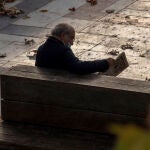 Un hombre lee un periódico sentado en un banco de la Plaza Nueva en Sevilla
