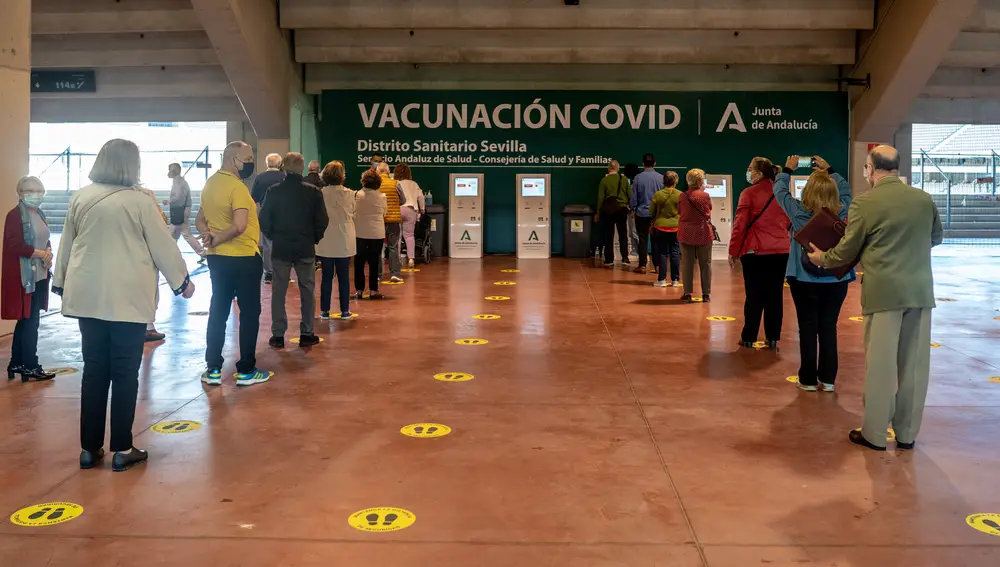 Varias personas esperan su turno para recibir la vacuna contra el Covid-19 en el Estadio de La Cartuja
