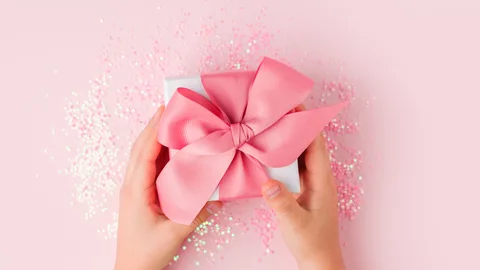 Manos de un niño que sostienen un regalo con lazo rosa