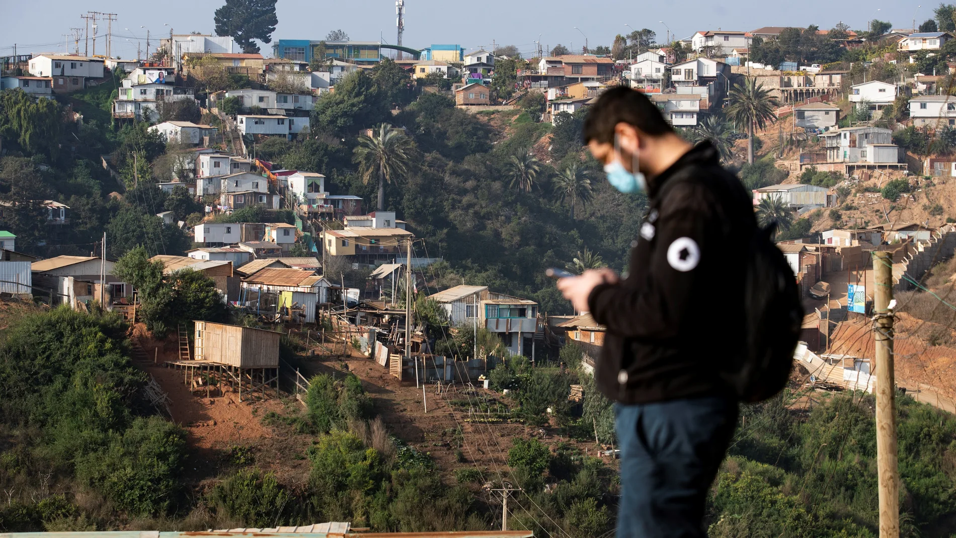 Un trabajador de la ONG TECHO-Chile es visto junto a uno de los cerros poblados de viviendas del Campamento Felipe Camiroaga el 30 de abril de 2021, en la ciudad de Viña del Mar (Chile).