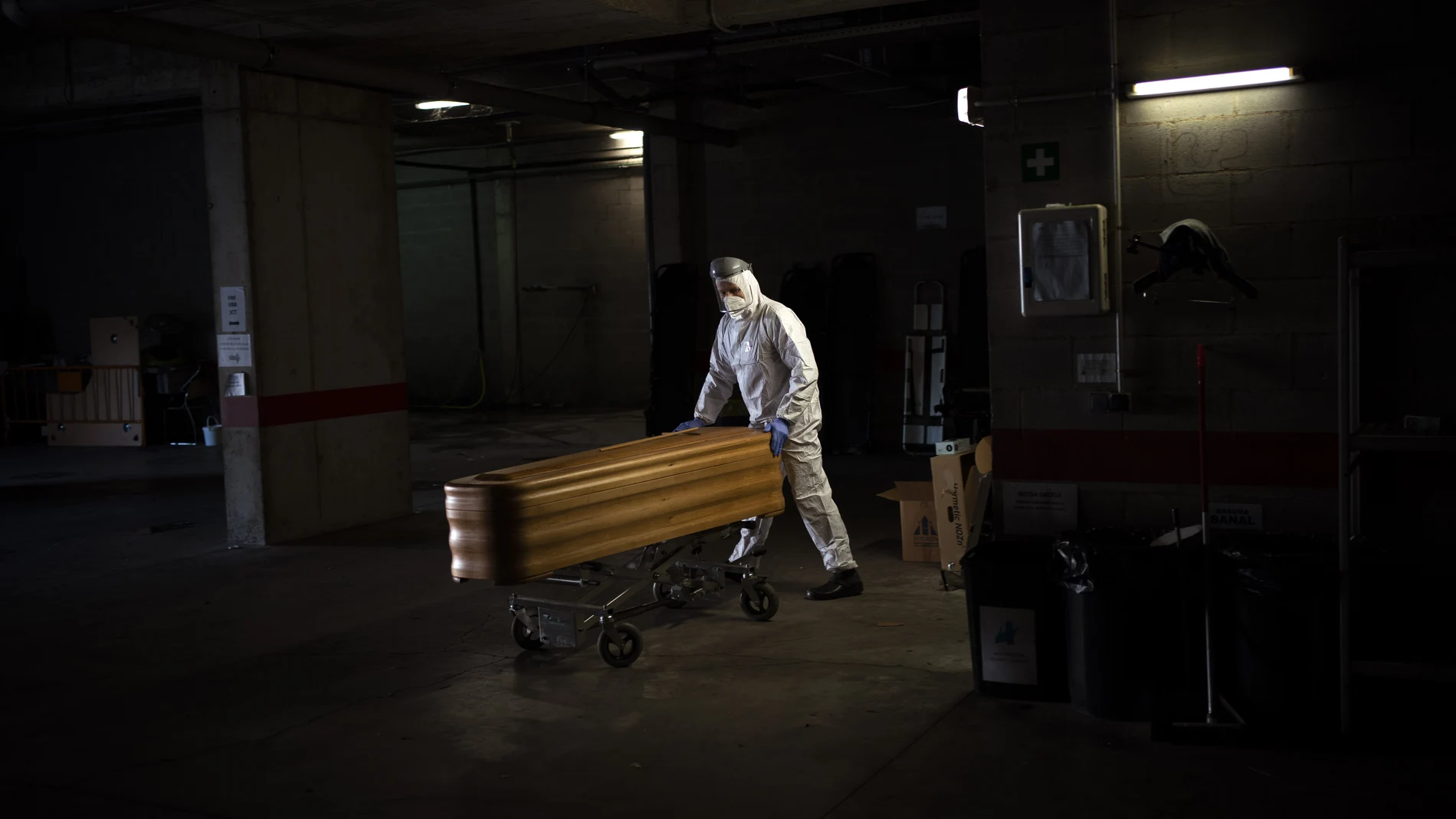 El trabajador de una funeraria traslada un féretro en un mortuorio de Gerona