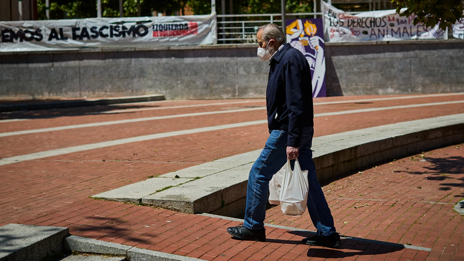Un hombre camina con las bolsas de la compra por la "Plaza Roja" de Vallecas