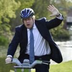 El "premier británico", Boris Johnson saluda sobre una bicicleta