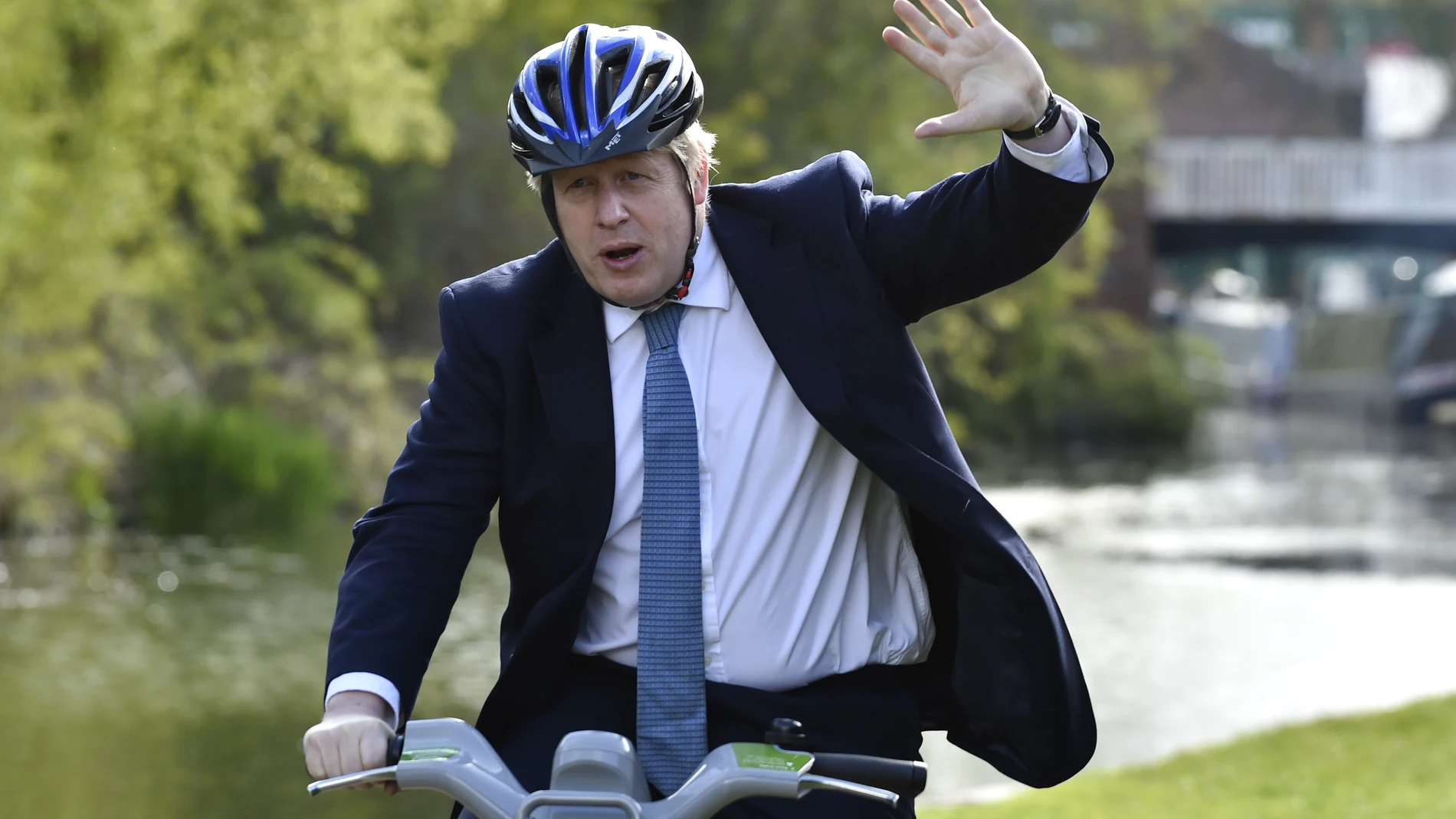 El "premier británico", Boris Johnson saluda sobre una bicicleta