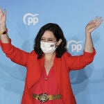 La presidenta de la Comunidad de Madrid y candidata a la reelección por el PP, Isabel Díaz Ayuso, saluda desde el balcón de la sede del partido