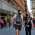 Varias personas pasean por las inmediaciones de la Puerta del Sol con mascarilla