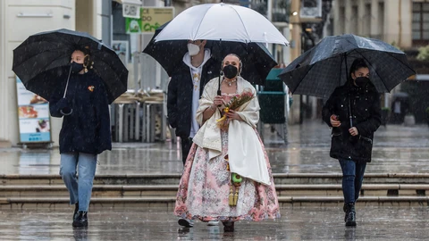 Una fallera se dirige a la Basílica de Valencia con un paraguas y un ramo de flores para la Virgen de los Desamparados, en Valencia, Comunidad Valenciana (España), a 18 de marzo de 2021