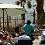 Varias personas en la terraza de un bar, frente a una playa de Lo Pagán