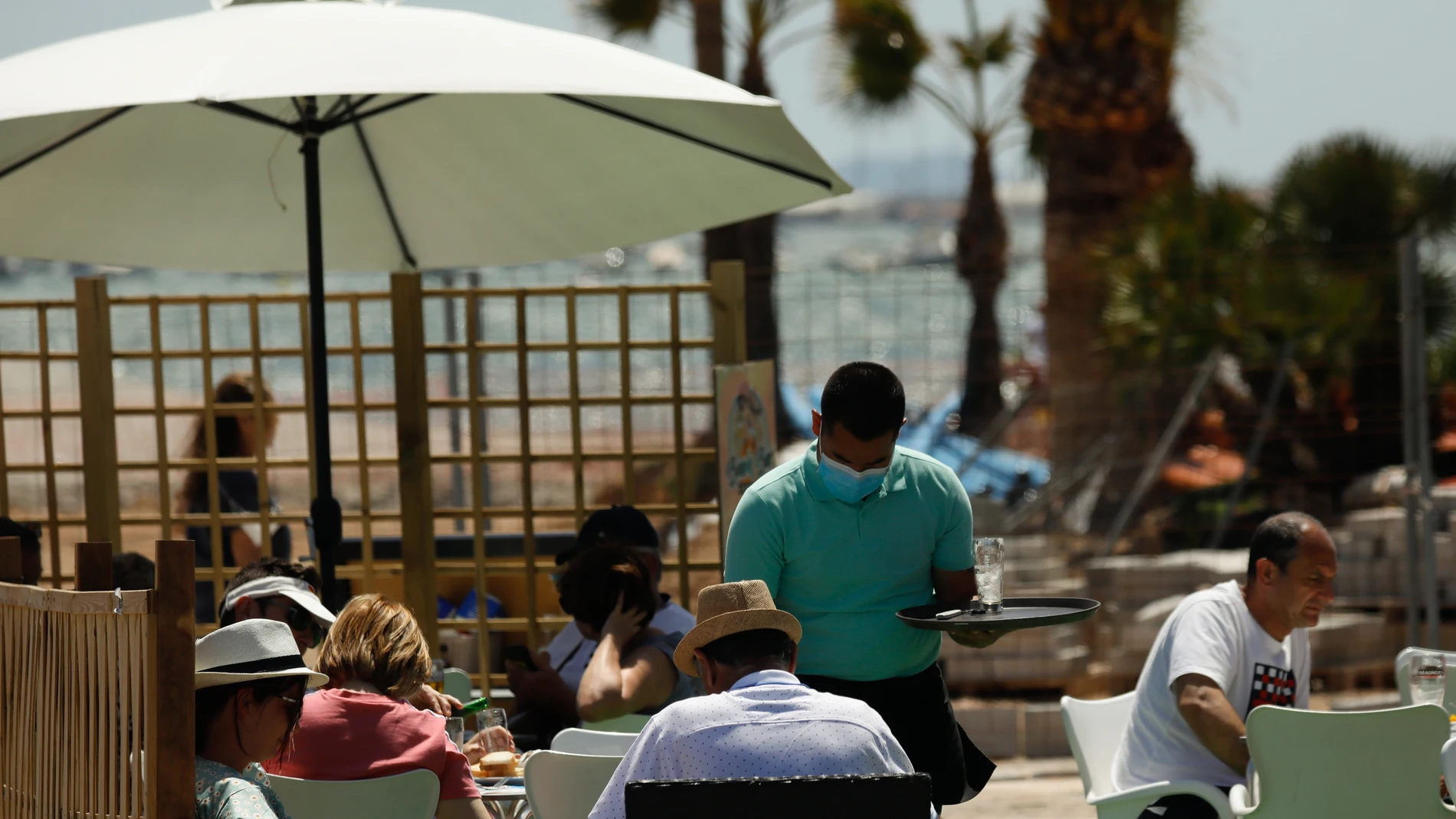 Varias personas en la terraza de un bar, frente a una playa de Lo Pagán