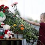 Una niña deja una flor cerca del colegio donde tuvo lugar la matanza