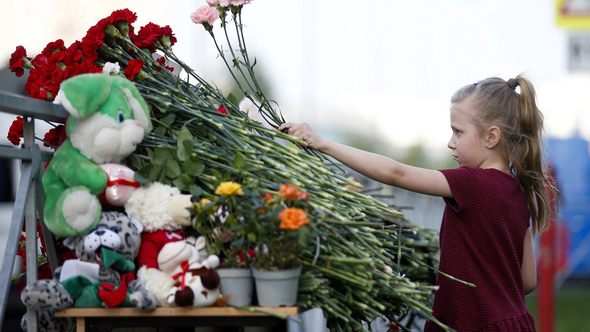 Una niña deja una flor cerca del colegio donde tuvo lugar la matanza