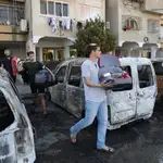 Residentes judíos pasan junto a automóviles quemados tras los disturbios ocurridos durante la noche entre residentes árabes y judíos en Lod, Israel, el 12 de mayo de 2021