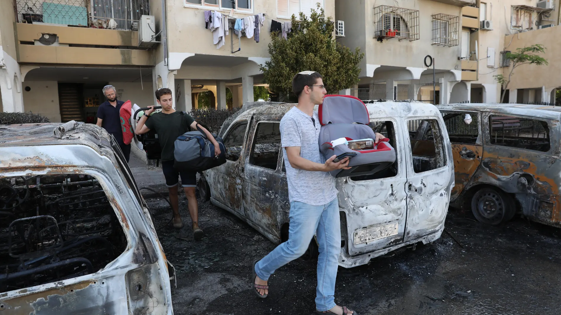 Residentes judíos pasan junto a automóviles quemados tras los disturbios ocurridos durante la noche entre residentes árabes y judíos en Lod, Israel, el 12 de mayo de 2021