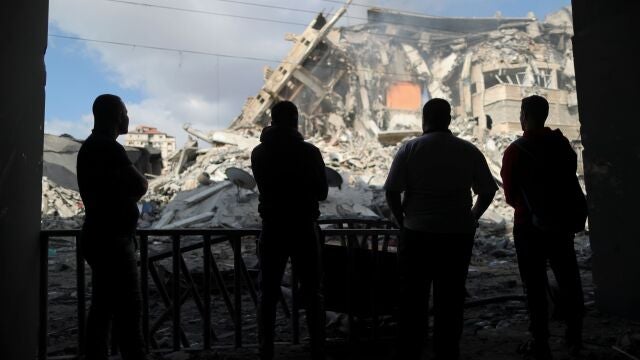 Palestinos observan los restos de una torre que fue destruida por los ataques aéreos israelíes, en la ciudad de Gaza el 13 de mayo