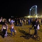 Varios jóvenes recogen sus pertenencias en la playa de la Barceloneta mientras la policía los desaloja