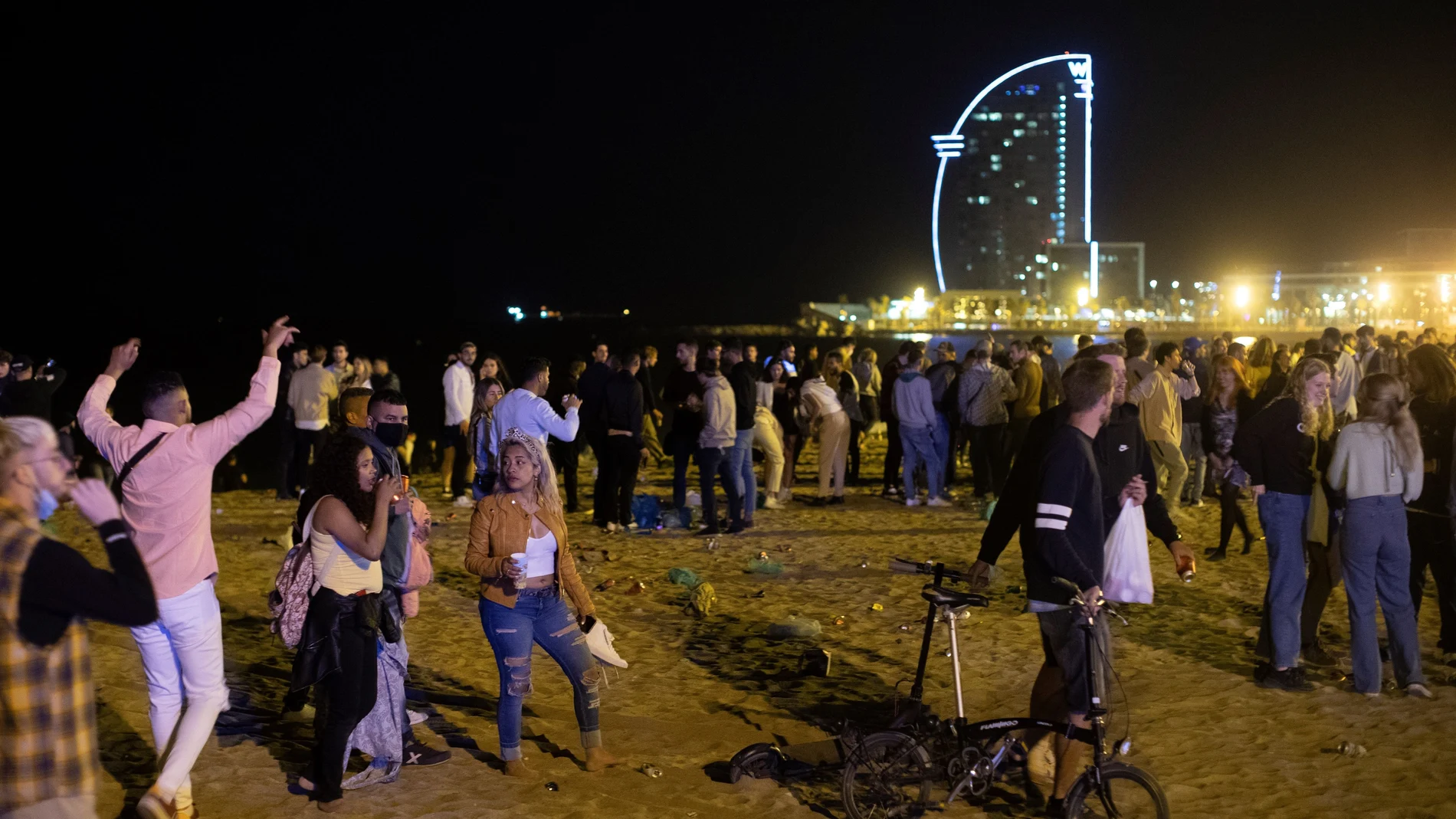 Varios jóvenes recogen sus pertenencias en la playa de la Barceloneta mientras la policía los desaloja