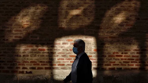 Un hombre pasea este lunes por una céntrica calle de Valladolid junto al reflejo de una cristalera