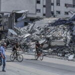 Jóvenes palestinos pasan delante de un edificio destruido por la aviación israelí en Ciudad de Gaza