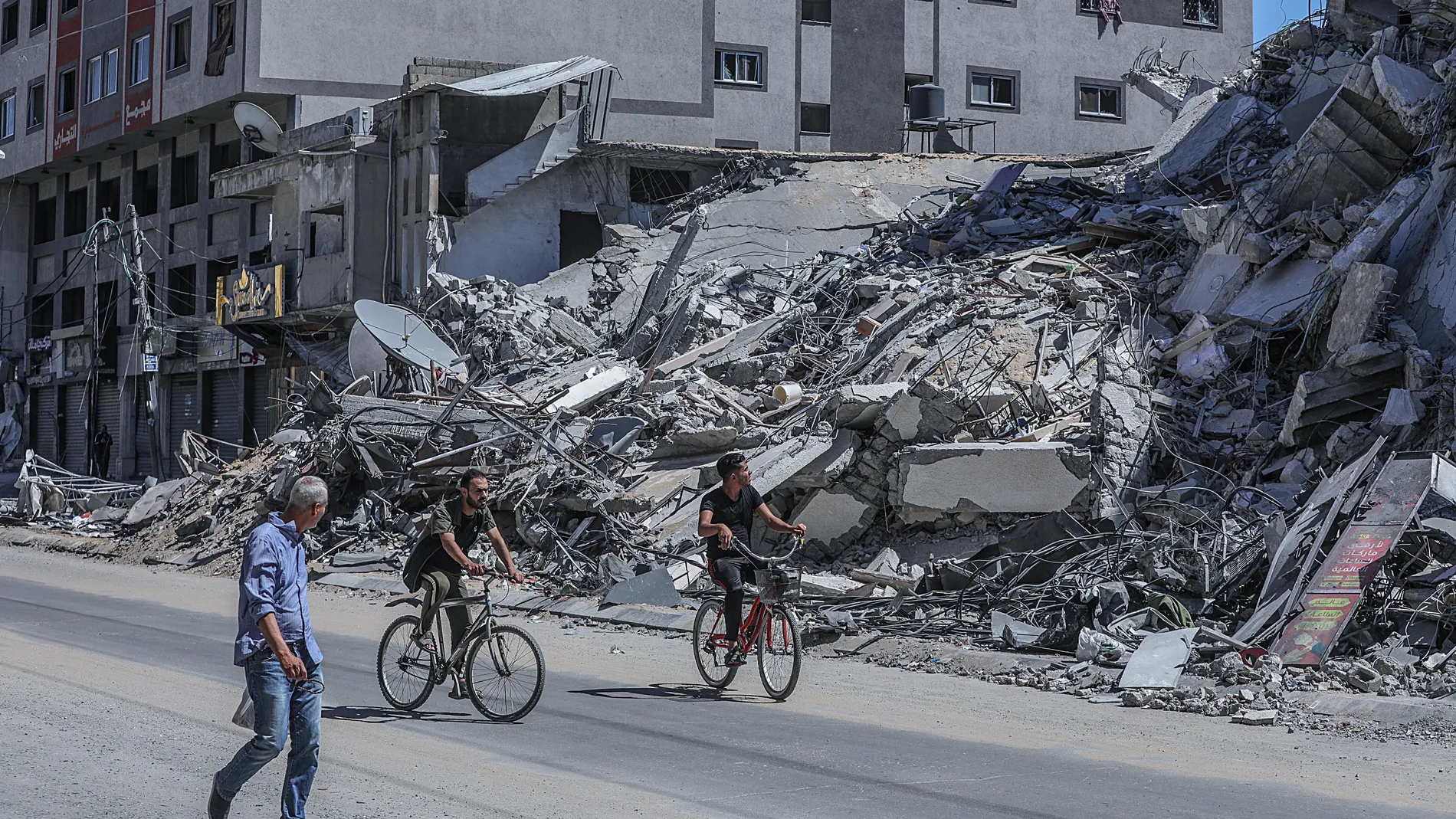 Jóvenes palestinos pasan delante de un edificio destruido por la aviación israelí en Ciudad de Gaza