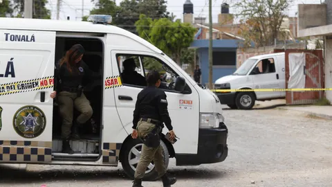 Policías municipales resguardan el área donde se encuentra una fosa clandestina, en Alamedas de Zalatitán, municipio de Tonalá, estado de Jalisco