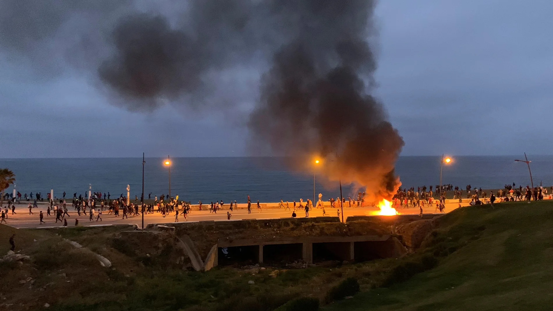 Decenas de emigrantes, a unos dos kilómetros al sur del Tarajal, se enfrentan con los antidisturbios marroquíes