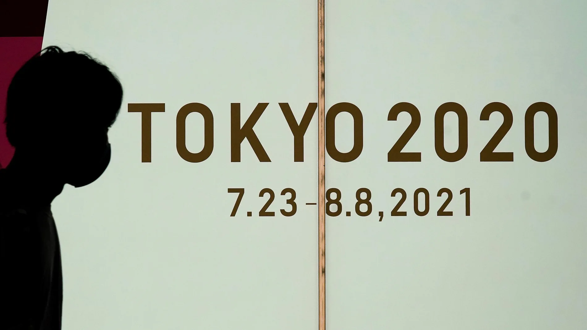 Un peatón camina al lado de un rótulo de los Juegos Olímpicos Tokio 2020
