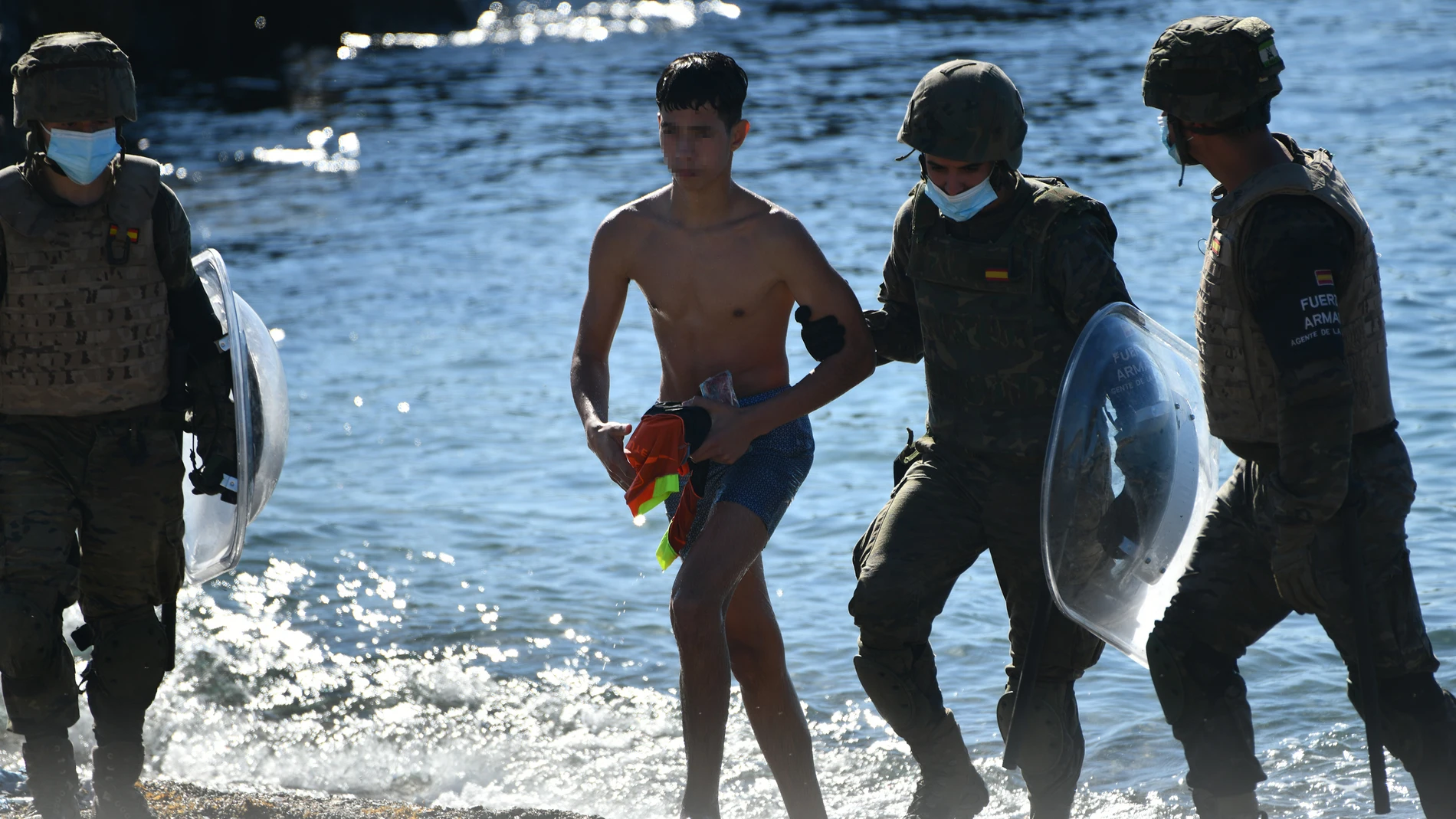 Un militar del ejército español ayuda a un menor migrante procedente de Marruecos a su llegada a Ceuta el pasado mayo