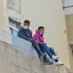 Dos niños sentados sobre un muro en la nave de primera acogida del polígono del Tarajal