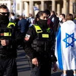 Una mujer con bandera de Israel junto a agentes de policía asiste a un mitin denominado 'Solidaridad con Israel y contra el antisemitismo' frente a la Puerta de Brandenburgo en Berlín, Alemania, el 20 de mayo