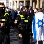 Una mujer con bandera de Israel junto a agentes de policía asiste a un mitin denominado &#39;Solidaridad con Israel y contra el antisemitismo&#39; frente a la Puerta de Brandenburgo en Berlín, Alemania, el 20 de mayo
