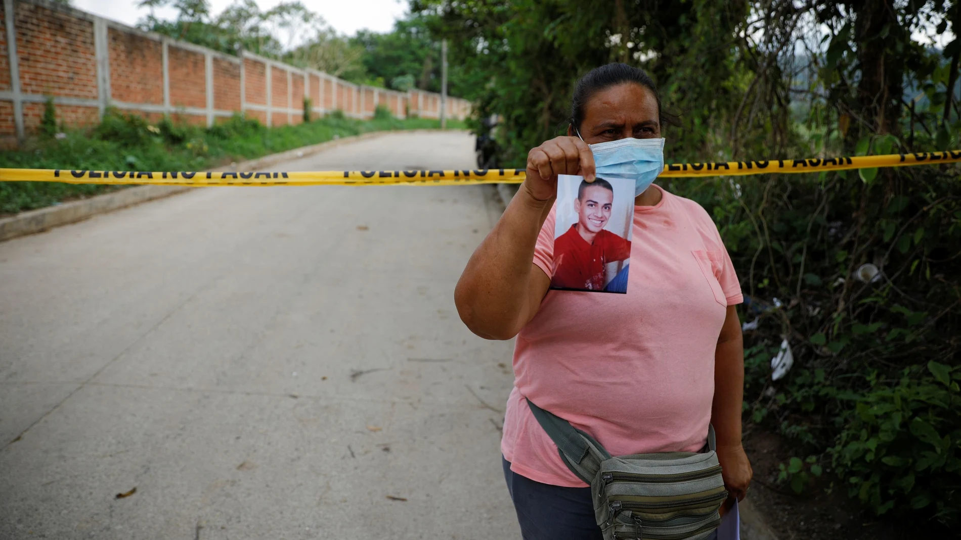 Marleny Barrientos shows a picture of her son who went missing six years ago and is believed to be at the site authorities are excavating a clandestine cemetery discovered at the house of a former police officer and containing as many as 40 bodies, most of them believed to be women in Chalchuapa, El Salvador May 20, 2021. REUTERS/Jose Cabezas