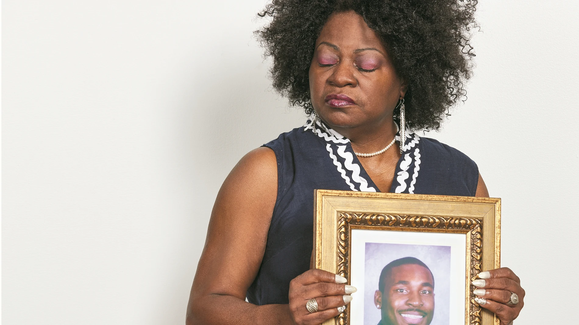 Beverly Smith junto a un retrato de su hijo asesinado por un agente de seguridad en 2015