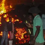 Varias personas frente a la lava del volcán cerca de Goma