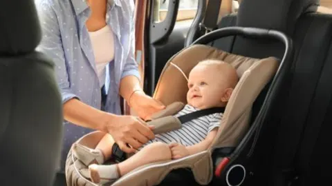 Una madre ajusta la silla de su bebé en el coche